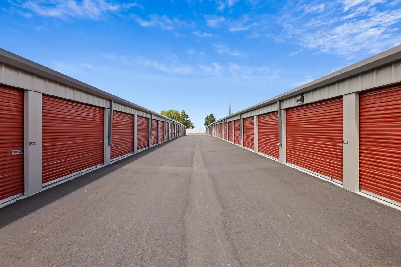 Wide paved drive-up aisle between rows of self-storage units